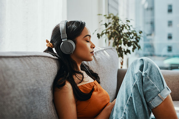 Femme relaxante écoutant de la musique sur ses écouteurs, les yeux fermés.