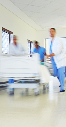 Des chirurgiens courent avec le lit d'un patient le long d'un couloir d'hôpital.